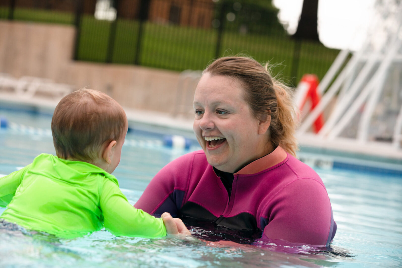 A woman and child in the water at a pool.