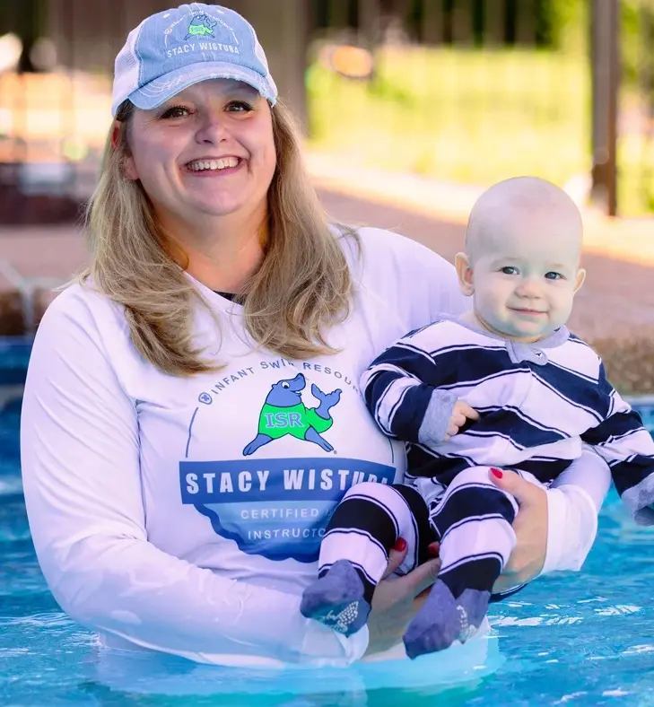 A woman holding a baby in the pool.