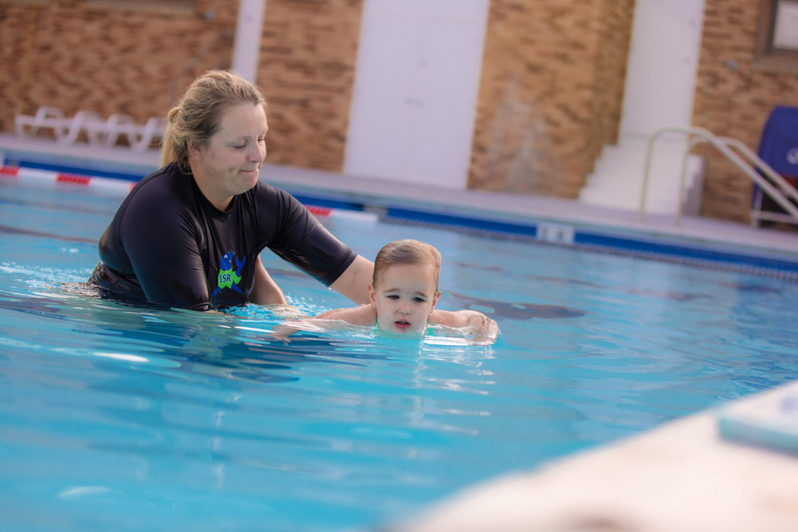 A woman and child in the water at an indoor pool.